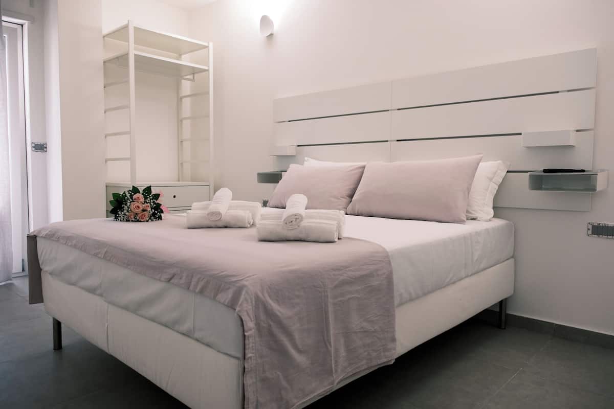 Ein modernes Schlafzimmer mit einem großen Bett, einem Einbauschrank und einem Nachttisch mit einer Lampe.