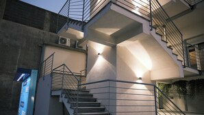 Un immeuble à plusieurs étages doté d’un escalier, de rampes en métal et d’un luminaire.