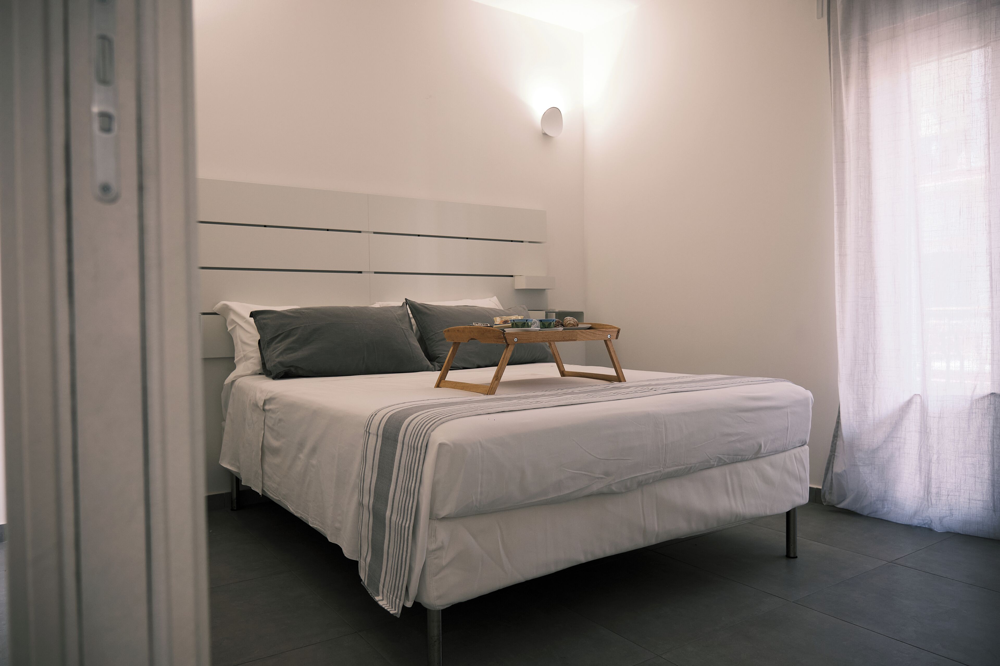 Un dormitorio moderno con cama, mesita de noche y lámpara de pared.