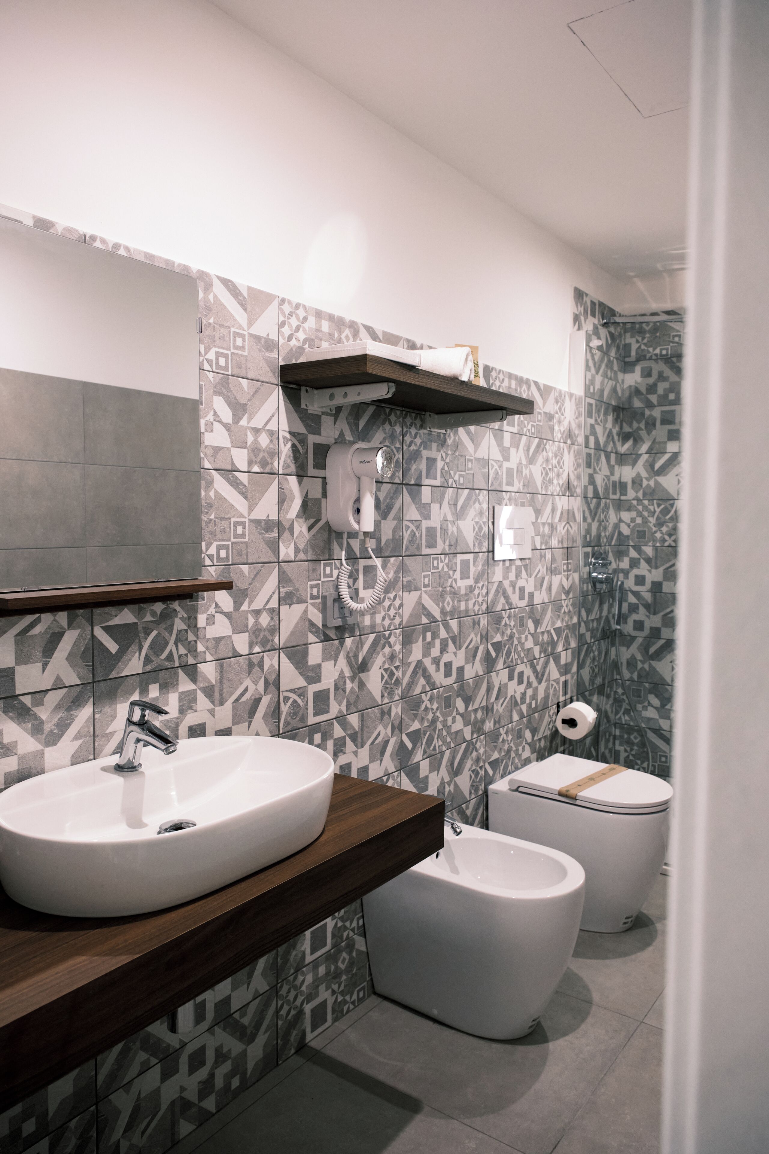 Une salle de bain moderne équipée d’un grand lavabo, d’un bidet, de toilettes et d’un porte-serviettes.