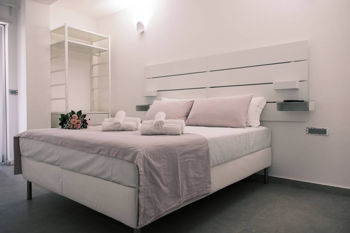 Ein modernes Schlafzimmer mit einem Bett, einem Einbauschrank und einem Nachttisch.