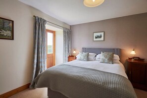 A bedroom with a large bed, two bedside tables, a window with curtains, and a framed picture on the wall. - The Stable at Carr Edge Farm (Newbrough)