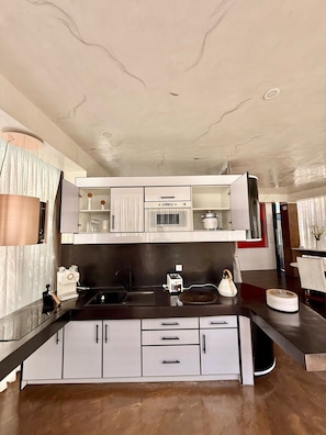 A modern kitchen with a central island, upper cabinets, and a microwave.