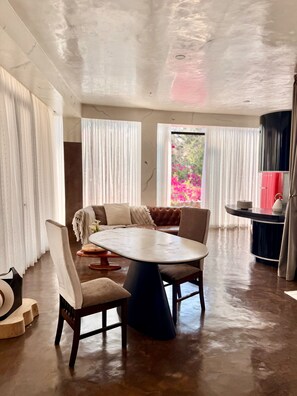 A modern dining area with a round table, chairs, a sofa, and a kitchen counter.