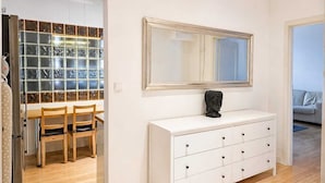 A room with a white dresser, a mirror, and a Buddha statue. There is a wooden dining table with chairs. - City View Apartment near Nowy Świat (Warsaw)