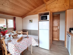 A wooden interior with a dining table, chairs, a refrigerator, a microwave, and a small kitchen area. - Natural chalet, pets allowed - 6 guests (Usson-en-Forez)