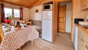 Une cuisine de taille réduite équipée d’un four à micro-ondes, d’un réfrigérateur et de meubles de rangement en bois.