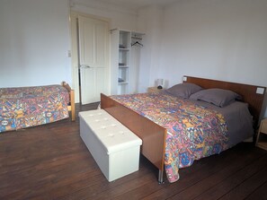 Une chambre à coucher avec un lit, un banc, une armoire et une étagère.
