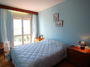 A bedroom with a bed, a nightstand, a lamp, and two framed pictures on the wall. - Apartment near beach and port - 6 guests (Llançà)