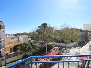 A balcony with a blue railing overlooking a street with parked cars and a red-roofed building. - Apartment near beach and port - 6 guests (Llançà)