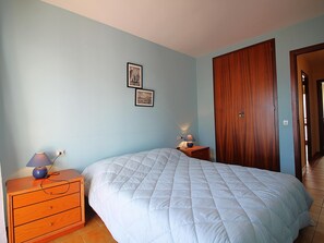 Un dormitorio con cama, cómoda, mesita de noche y dos cuadros en la pared.