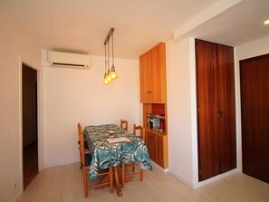 Un comedor con mesa, sillas, una lámpara colgante y un mueble de madera con libros.