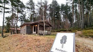 A wooden cabin with a porch, surrounded by trees. - Nature chalet, pets welcome - 6 guests (Usson-en-Forez)