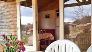 A wooden cabin with a dining area, a table with a map, and a vase of flowers. - Nature chalet, pets welcome - 6 guests (Usson-en-Forez)