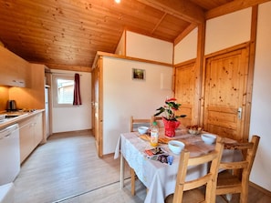 Eine kompakte Küche mit Holzausbau, einem Esstisch mit Stühlen und einer Holztür.