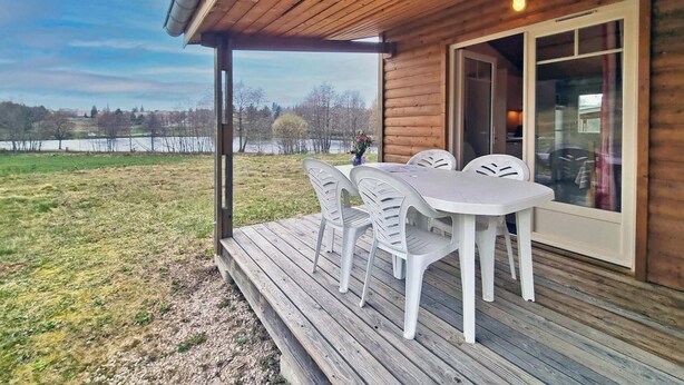 A wooden cabin with a deck, a table, and chairs.