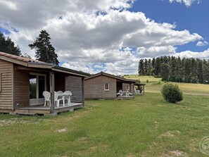 Two wooden cabins with outdoor seating, surrounded by a grassy field and trees. - Chalet, pets welcome, preserved nature - 4 guests (Usson-en-Forez)