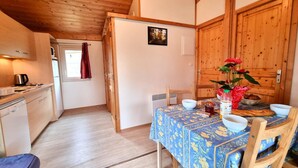 Una cocina acogedora con armarios de madera, una mesa de comedor con mantel floral y una puerta de madera.