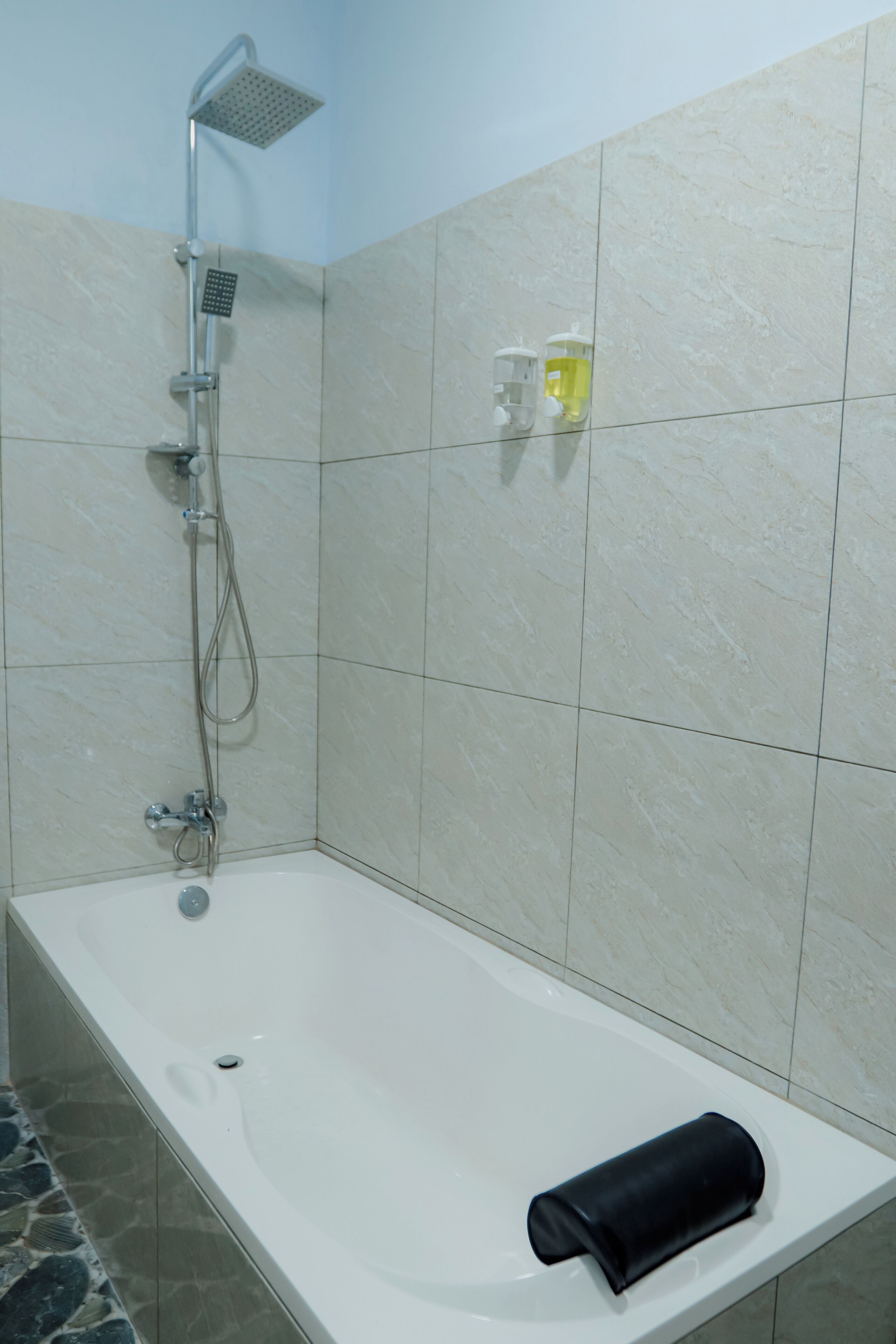 A bathroom with a bathtub, a showerhead, and a towel on the edge.