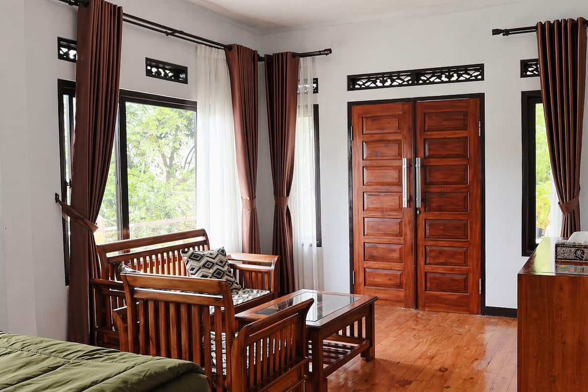 A room with a bed, a wooden bench with cushions, a table, and a wardrobe.