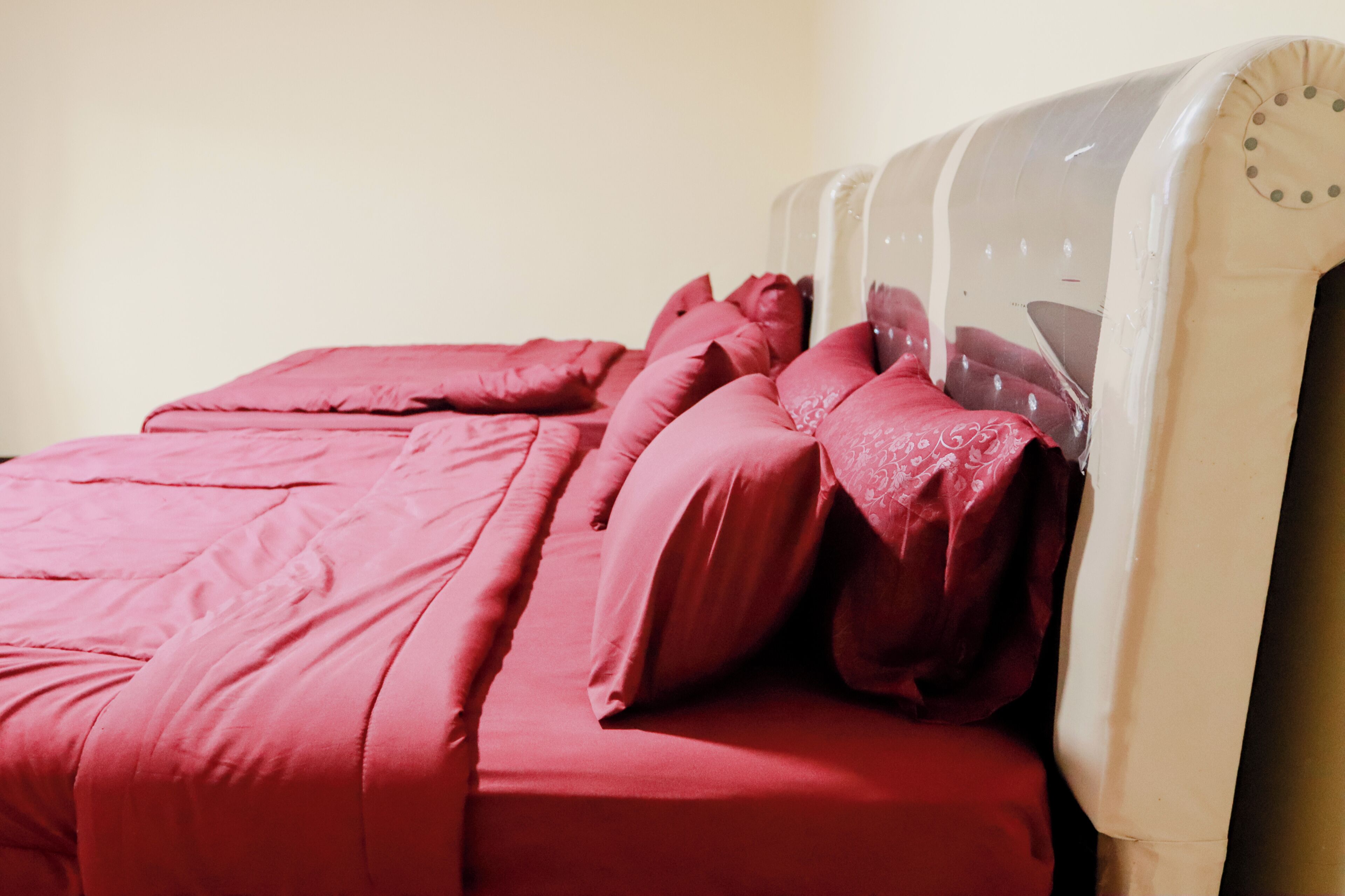 Una cama con cabecera blanca y ropa de cama roja.