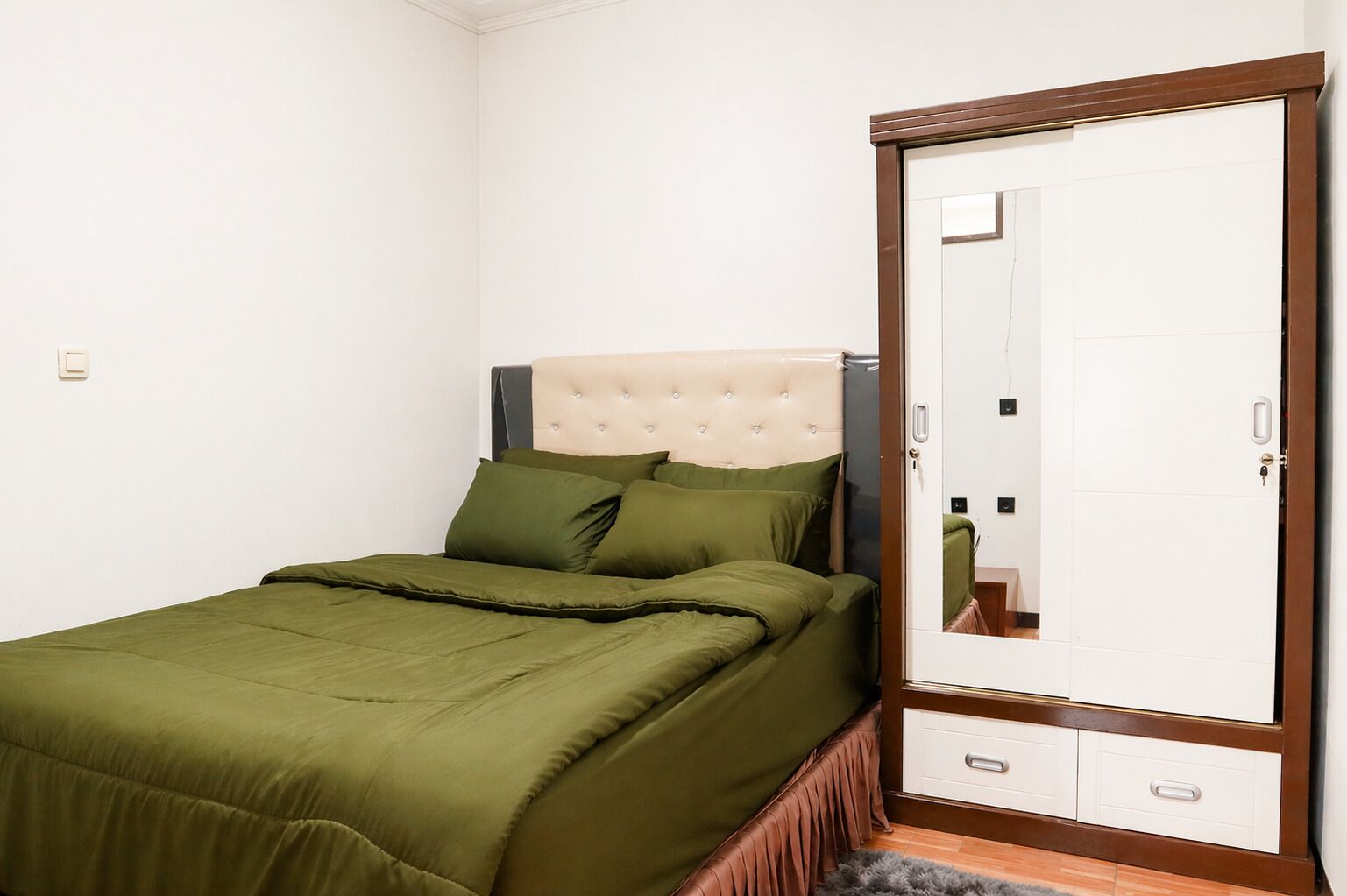 Un dormitorio con cama, armario y espejo.