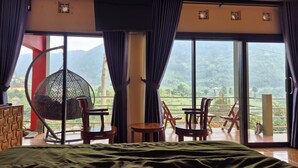 Un dormitorio con una cama grande, un sillón colgante y una mesa.