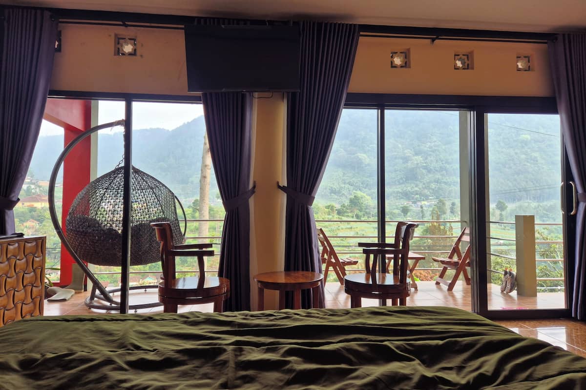 A bedroom with a large bed, a hanging chair, and a table.