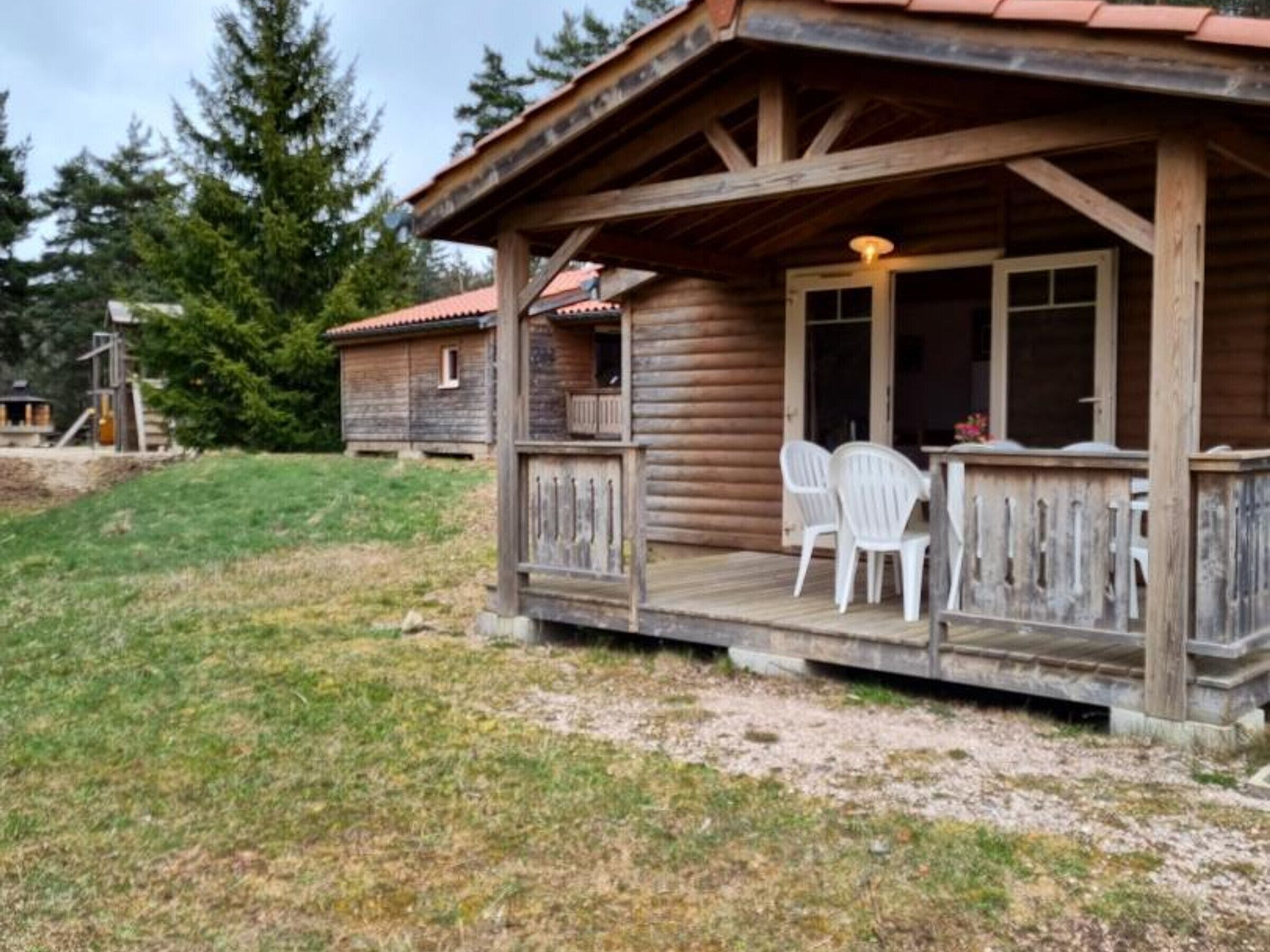 Eine Holzhütte mit Veranda, zwei weißen Stühlen und einem Tisch.