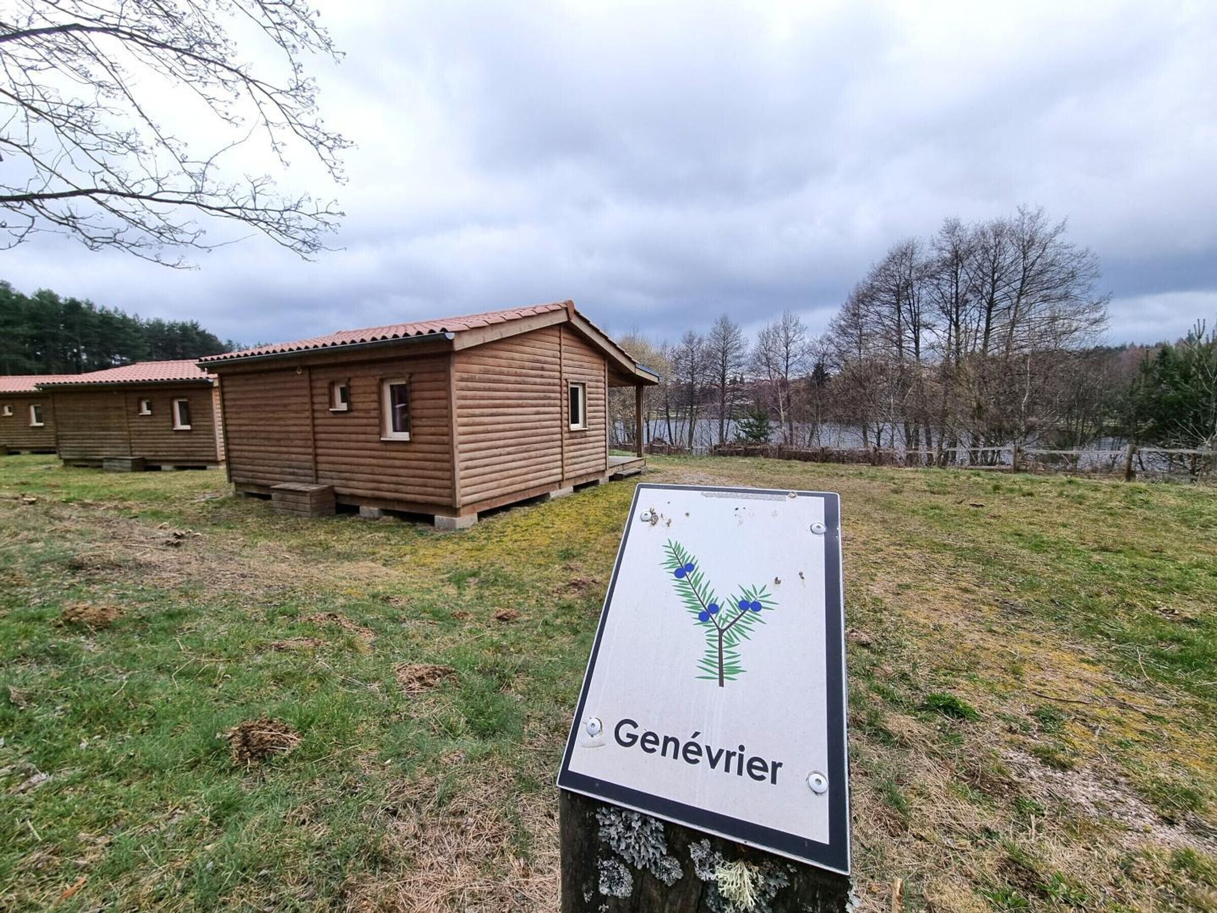 A wooden cabin with a sign labeled 'Genévrier' in front.
