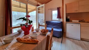 Habitación compacta con mesa de comedor, cama, kitchenette y ventanas amplias.
