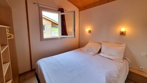 Un dormitorio con cama, ventana con vistas y techo de madera.