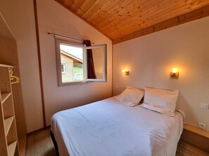 A bedroom with a bed, a window with a view, and a wooden ceiling. - Chalet, pets welcome in Haut-Forez - 4 guests (Usson-en-Forez)
