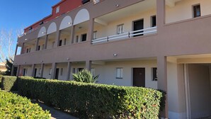 Un edificio a più piani con balconi, un tetto rosso e una facciata beige.
