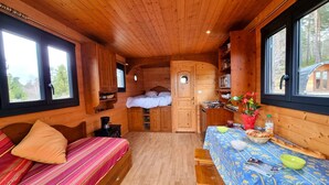 Een gezellig chalet van binnen, met een bed, een kleine kitchenette en een eethoek.