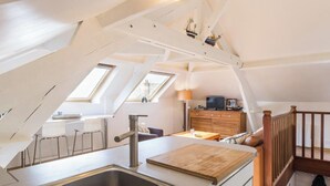 A modern loft apartment with a kitchen, dining area, and a staircase leading to a lofted bedroom. - Bright apartment, pets welcome - 2 guests (Barneville-Carteret)
