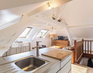 Eine moderne Loft-Wohnung mit Küche, Essbereich und einer Wendeltreppe zum erhöhten Schlafbereich.