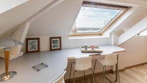 A modern loft bedroom with a skylight, a curved white desk, two white chairs, and framed pictures on the wall. - Bright apartment, pets welcome - 2 guests (Barneville-Carteret)