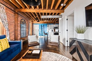 A spacious living area with a blue sofa, two striped chairs, a wooden coffee table, and a kitchen in the background. - We Love You Dolly P! (Nashville)