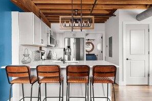 A modern kitchen with white cabinets, stainless steel appliances, and a central island with bar stools. - We Love You Dolly P! (Nashville)