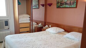 Une chambre à coucher avec un grand lit, une table de chevet avec une lampe, une armoire et un radiateur.