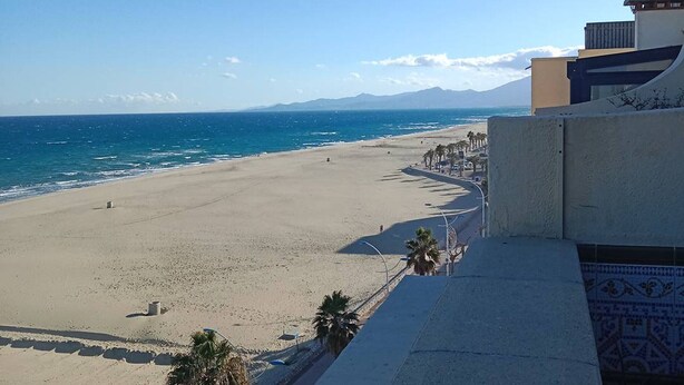 Une plage offrant une vue dégagée sur l’océan et les montagnes lointaines.