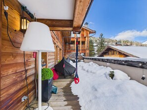 Une cabane en bois avec un porche couvert, une lampe et un paysage enneigé.