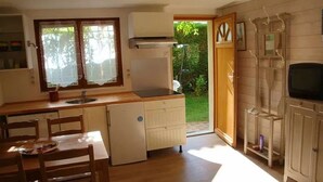 Una cocina compacta con comedor, un refrigerador empotrado y un televisor sobre un mueble de madera.