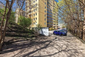 Un edificio residencial de varios pisos con balcones, un camino pavimentado y coches aparcados.