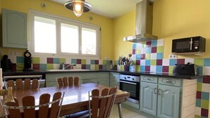A kitchen with a dining table, chairs, a microwave, and a stove. - Spacious house, near the beach - 6 guests (Saint-Pierre-d'Oléron)