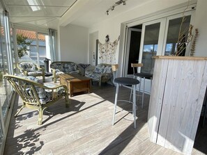 Ein sonnendurchflutetes Zimmer mit Korbmöbeln, einem Holztisch und einer Bar.