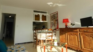 A living room with a dining area, a television, and a cabinet. - Apartment with parking, air conditioning - 4 guests (Bormes-les-Mimosas)
