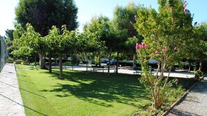 A park with green grass, trees, benches, and a gravel path. - Apartment with parking, air conditioning - 4 guests (Bormes-les-Mimosas)