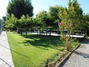 Ein Park mit grünem Gras, Bäumen, Bänken und einem Kiesweg.